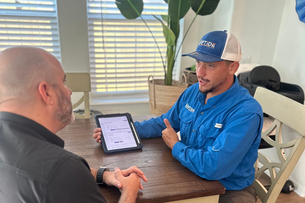 A Riptide Mechanical technician and a homeowner at a dining table going through the options on a tablet