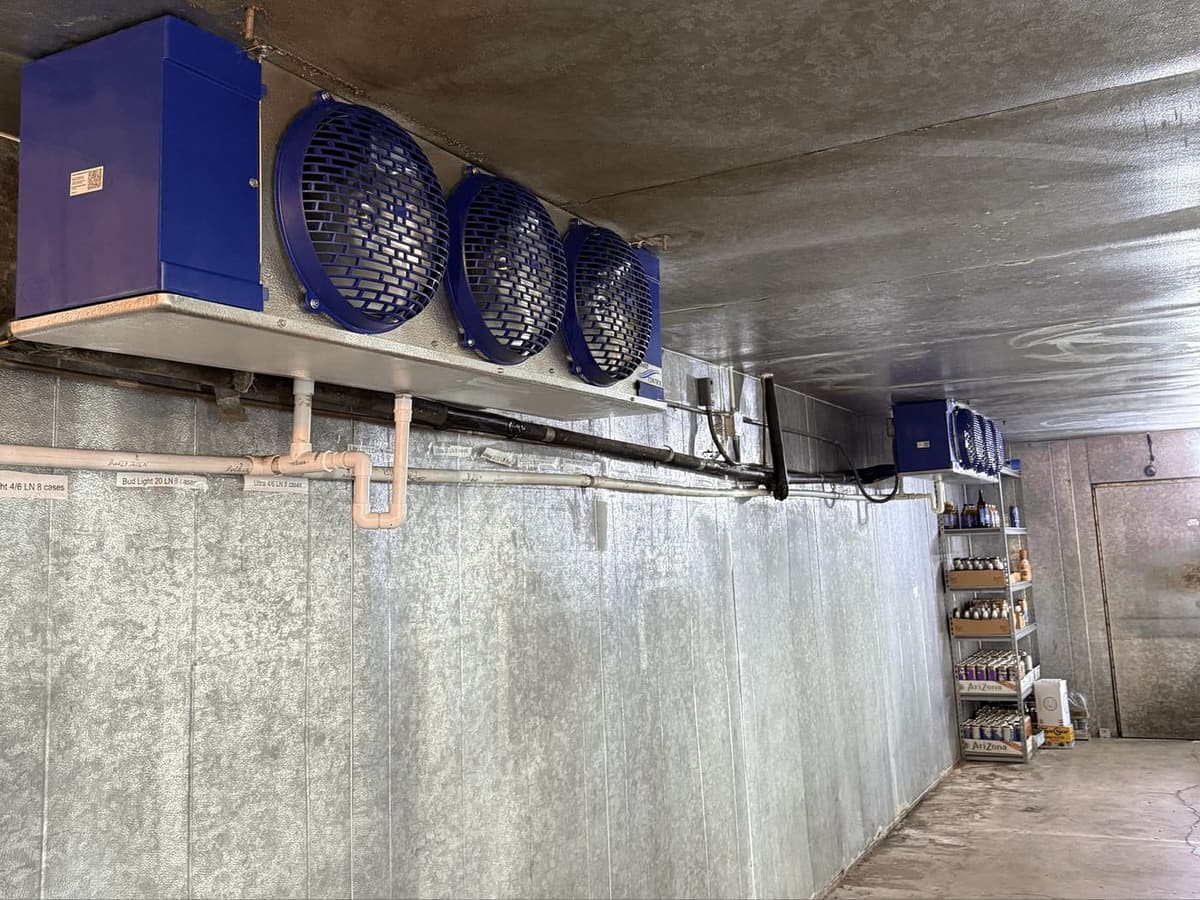 The inside of a commercial walk in beverage cooler stocked with product
