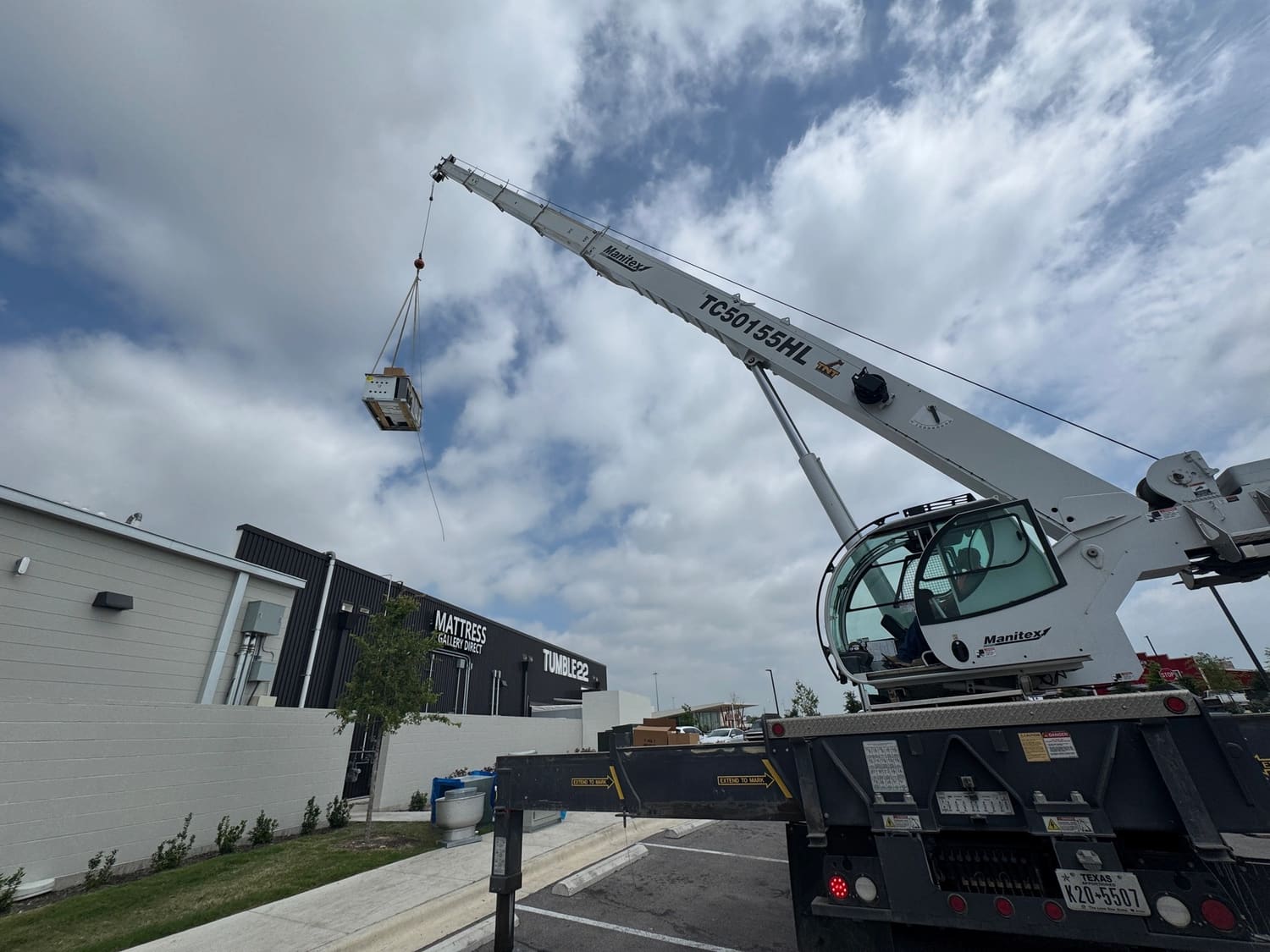 A crane lifting a rooftop HVAC unit into position on a commercial building