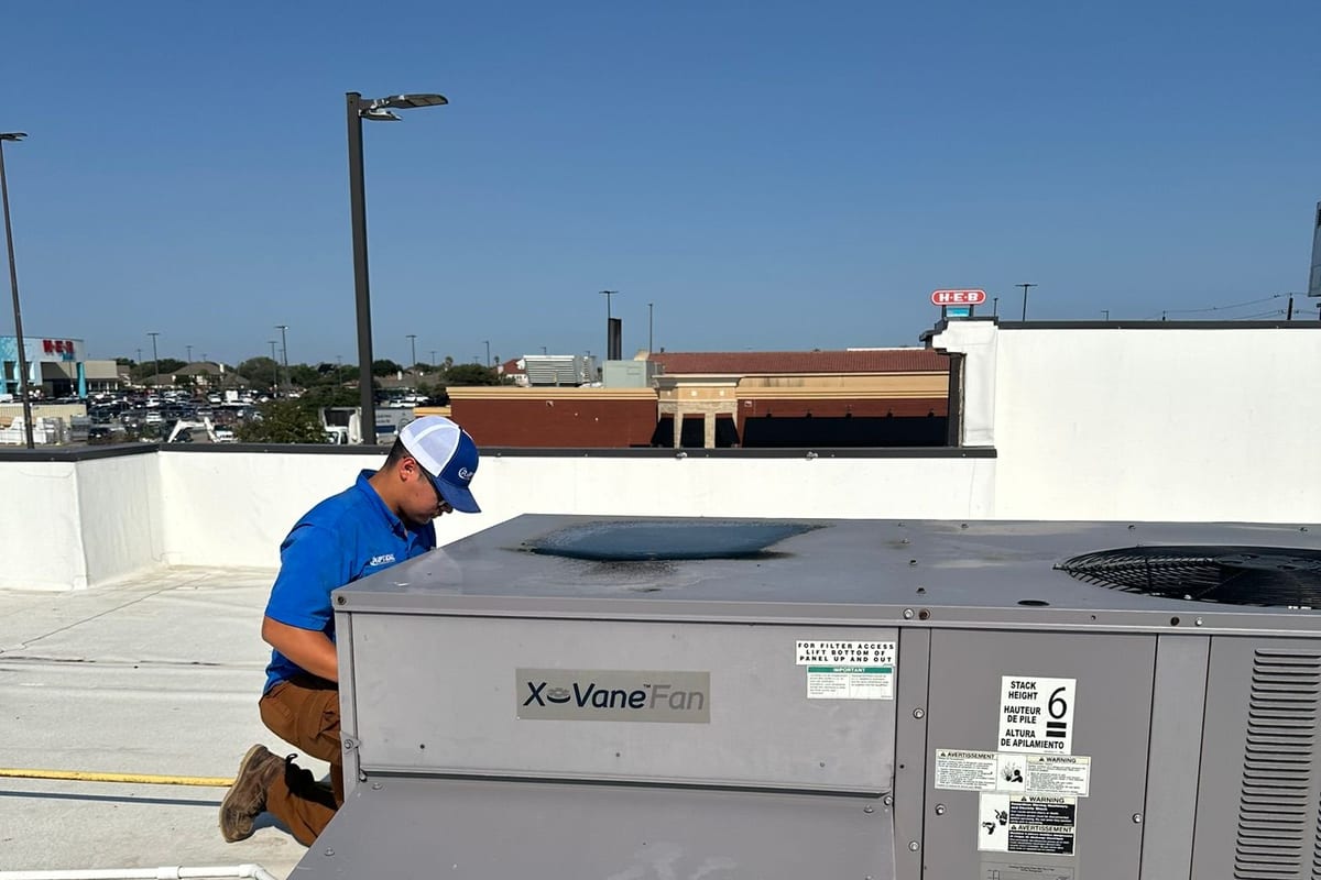 A Riptide Mechanical technician working on a packaged rooftop unit on a commercial building roof