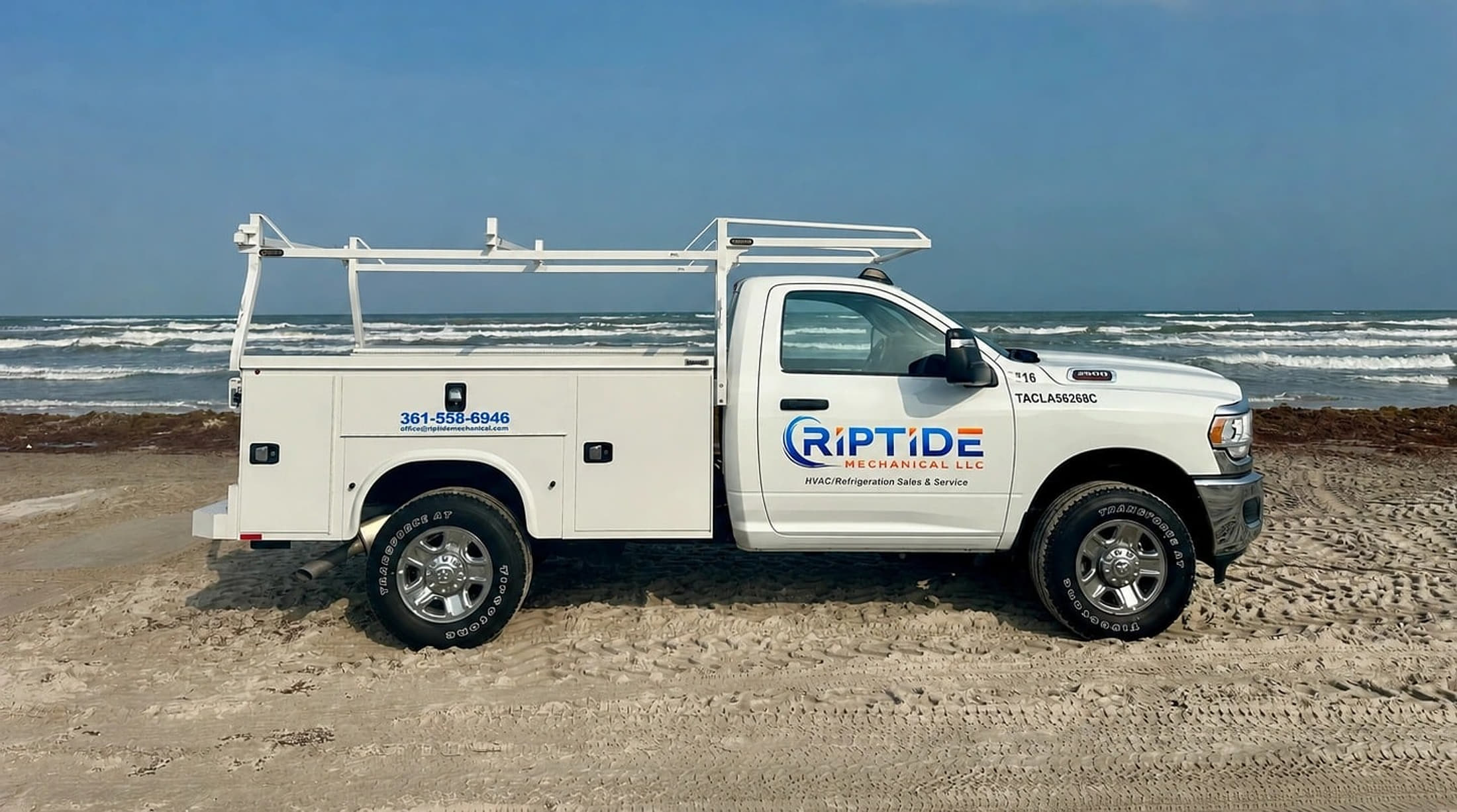 A Riptide Mechanical service truck parked on the sand of the Texas coast with the Gulf behind it