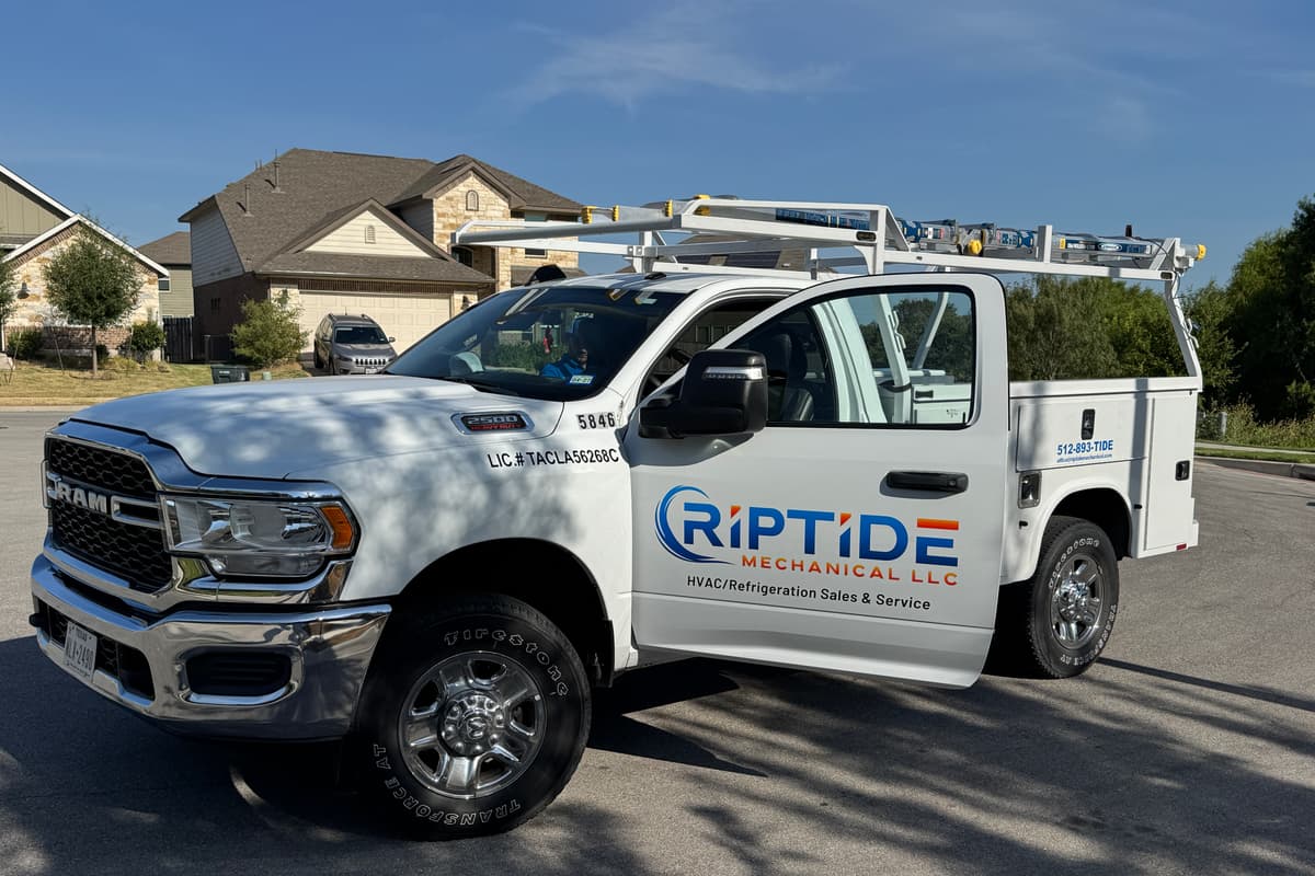 A Riptide Mechanical service truck parked on the street of an Austin neighborhood, the Austin number 512-893-TIDE on the body
